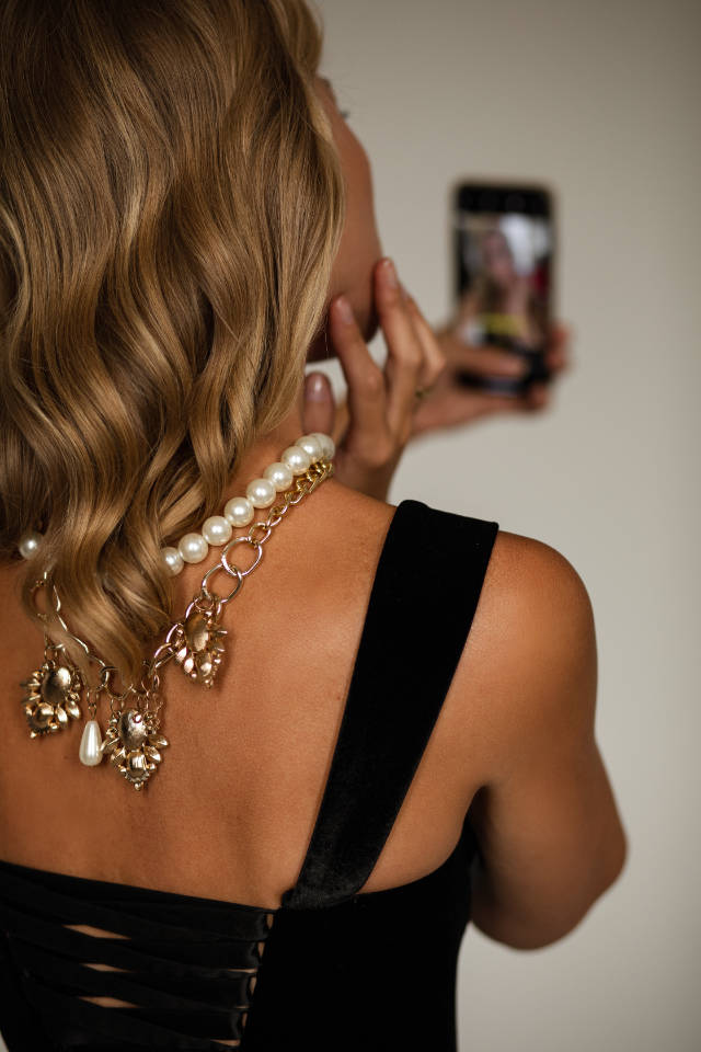 Pretty blonde woman with pearl necklace taking a selfie